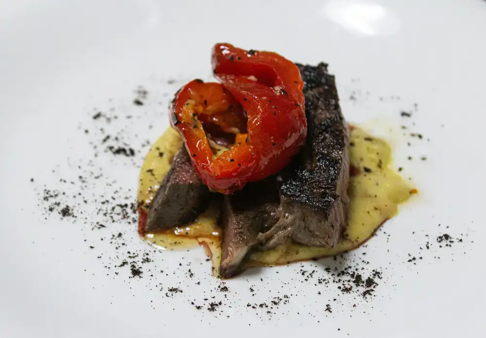 Chef profesional decorando un plato de alta cocina con microbrotes